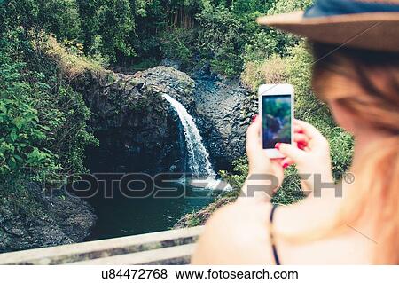 "Over shoulder view of female tourist photographing waterfall on smartphone, Haleakala, Hawaii, USA" View Large Photo Image Stock Photo - "Over shoulder view of female tourist photographing waterfall on smartphone, Haleakala, Hawaii, USA". Fotosearch