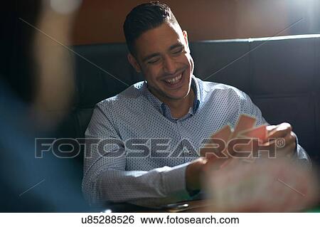 Stock Photograph - Over shoulder view of men playing cards in traditional UK pub. Fotosearch