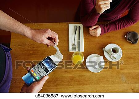 Overhead cropped view of waiter removing receipt from credit card machine in restaurant View Large Photo Image Stock Photo - Overhead cropped view of waiter removing receipt from credit card machine in restaurant. Fotosearch