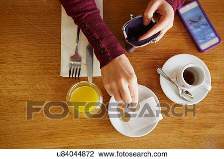 Stock Image - Overhead cropped view of woman leaving gratuity in restaurant. Fotosearch