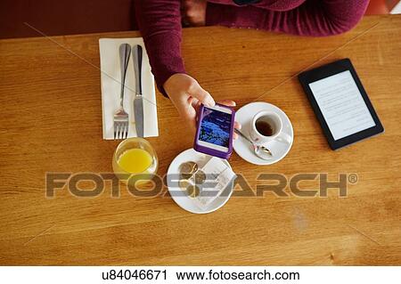 Overhead cropped view of woman reading smartphone text in restaurant View Large Photo Image Stock Image - Overhead cropped view of woman reading smartphone text in restaurant. Fotosearch