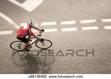 Stock Image - Overhead view of cyclist speeding on urban road in racing cycle race. Fotosearch