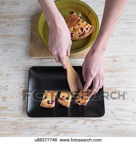 Overhead view of female hands placing cake onto dish at kitchen counter View Large Photo Image Stock Photograph - Overhead view of female hands placing cake onto dish at kitchen counter. Fotosearch