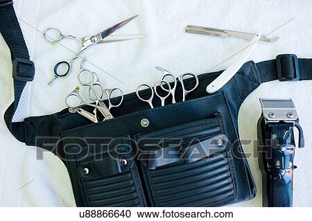 Stock Image - Overhead view of hairdressers tool belt with scissors, hair clippers and straight razor. Fotosearch