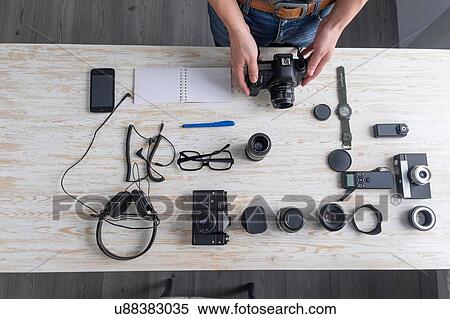 Stock Photography - Overhead view of male photographer preparing camera on studio desk. Fotosearch