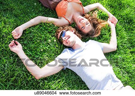 Picture - Overhead view of romantic young couple lying on garden lawn. Fotosearch