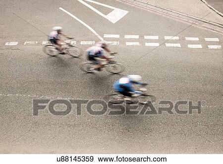 Stock Photo - Overhead view of three cyclists speeding on urban road in racing cycle race. Fotosearch