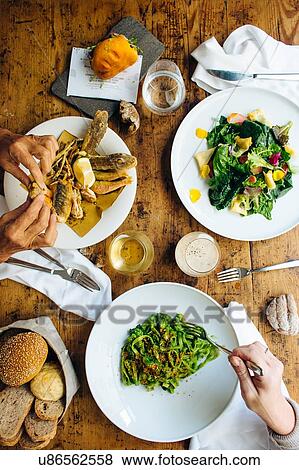 Overhead view of two women eating Italian lunch with fried seafood, spring salad and tagliatelli View Large Photo Image Stock Photo - Overhead view of two women eating Italian lunch with fried seafood, spring salad and tagliatelli. Fotosearch