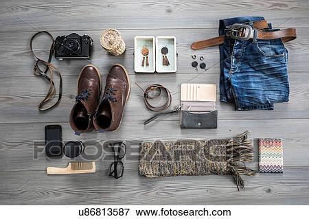 Stock Photo - Overhead view of variety of objects including camera, jeans and smartphone. Fotosearch