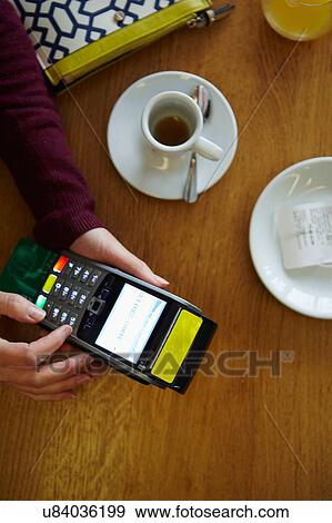 Overhead view of womans hands typing number on credit card machine in restaurant View Large Photo Image Stock Photo - Overhead view of womans hands typing number on credit card machine in restaurant. Fotosearch