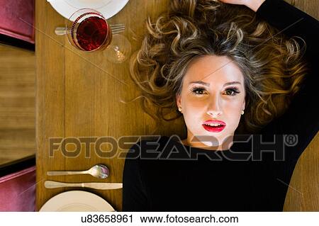 Overhead view of young woman lying on dining table View Large Photo Image Stock Image - Overhead view of young woman lying on dining table. Fotosearch