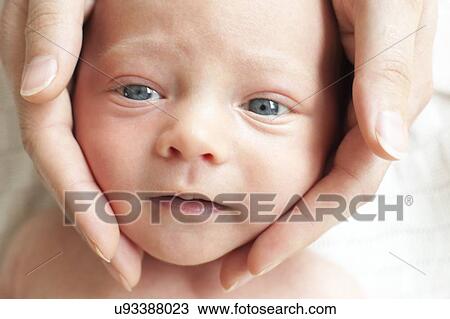 Stock Image - Person touching newborn's face. Fotosearch