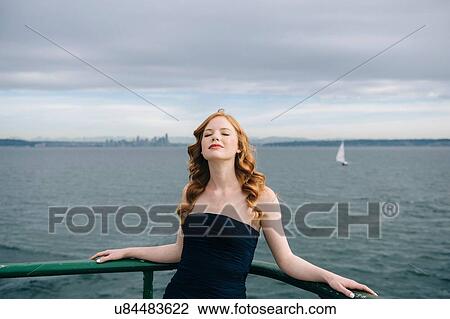 Stock Image - "Portrait of beautiful young woman with eyes closed on passenger ferry crossing Puget Sound, Seattle, USA". Fotosearch
