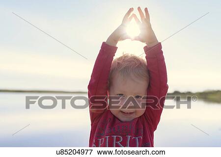 Portrait of cute girl at lake with sun between her fingers, Hafravatn, Iceland View Large Photo Image Stock Photo - Portrait of cute girl at lake with sun between her fingers, Hafravatn, Iceland. Fotosearch
