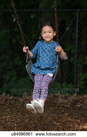 Portrait of cute girl swinging on playground swing View Large Photo Image Stock Image - Portrait of cute girl swinging on playground swing. Fotosearch