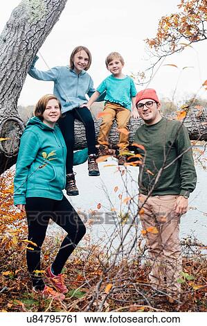 Stock Image - "Portrait of family, children sitting on tree". Fotosearch