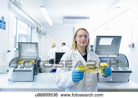 Stock Photograph - Portrait of female scientist with oil sample in testing facility. Fotosearch