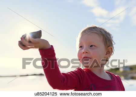 Portrait of girl holding stone to sun at lake, Hafravatn, Iceland View Large Photo Image Stock Photography - Portrait of girl holding stone to sun at lake, Hafravatn, Iceland. Fotosearch