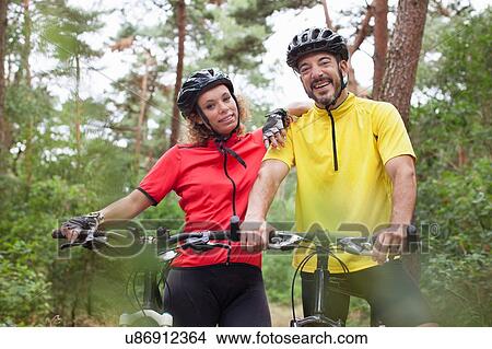 Picture - Portrait of happy mountain biking couple in forest. Fotosearch