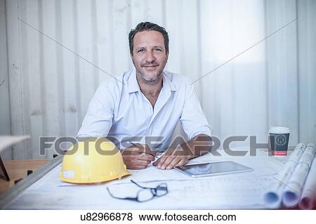 Stock Photo - Portrait of male construction foreman at desk in portable cabin. Fotosearch