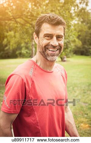 Stock Photo - Portrait of mature man wearing red t-shirt looking at camera smiling. Fotosearch
