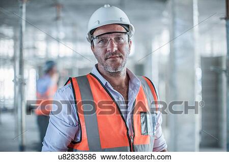 Stock Photograph - Portrait of mid adult male site manager on construction site. Fotosearch