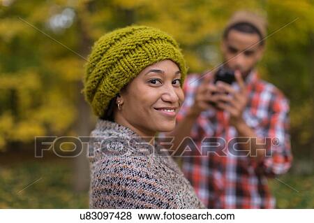Stock Photo - Portrait of mid adult woman being photographed by boyfriend in autumn forest. Fotosearch
