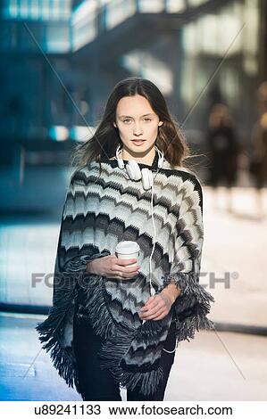 Stock Image - Portrait of mid adult woman wearing poncho strolling on city street. Fotosearch