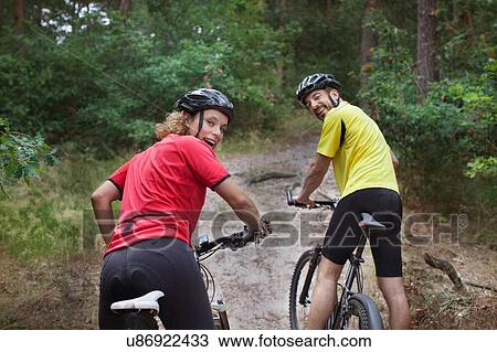 Portrait of mountain biking couple looking over their shoulders in forest View Large Photo Image Stock Image - Portrait of mountain biking couple looking over their shoulders in forest. Fotosearch