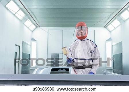 Stock Image - Portrait of worker paint spraying parts on automotive production line. Fotosearch