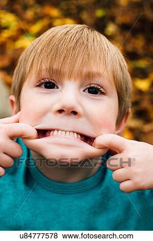 Stock Photo - "Portrait of young boy pulling face, close-up". Fotosearch