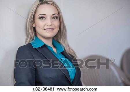 Stock Image - Portrait of young businesswoman with long blond hair sitting in office. Fotosearch