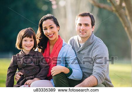 Portrait of young couple with daughter sitting on lap in park View Large Photo Image Stock Photo - Portrait of young couple with daughter sitting on lap in park. Fotosearch