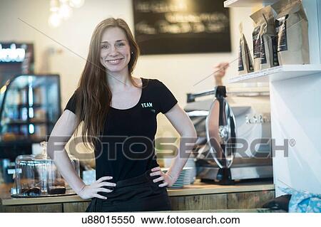 Portrait of young female waitress behind kitchen counter in cafe View Large Photo Image Stock Image - Portrait of young female waitress behind kitchen counter in cafe. Fotosearch