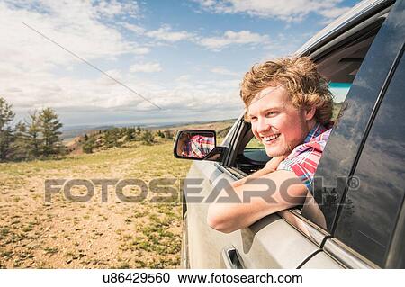 Stock Image - Portrait of young man looking out from off road vehicle window, Bridger, Montana, USA. Fotosearch