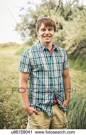 Portrait of young man standing in field with hands in pockets View Large Photo Image Stock Image - Portrait of young man standing in field with hands in pockets. Fotosearch