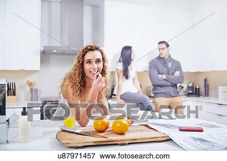 Stock Photo - Portrait of young woman eating breakfast cereal at kitchen counter. Fotosearch
