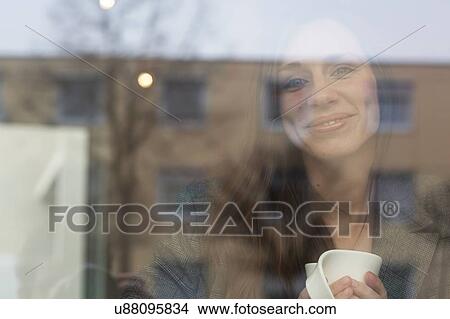 Portrait of young woman looking through cafe window View Large Photo Image Picture - Portrait of young woman looking through cafe window. Fotosearch