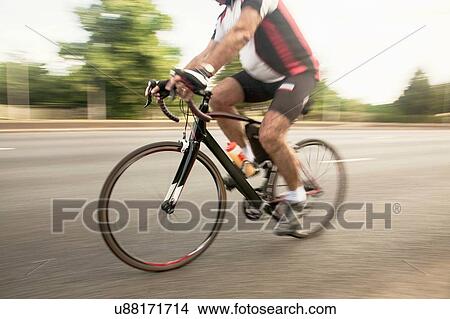 Racing cyclist speeding on urban road in racing cycle race View Large Photo Image Picture - Racing cyclist speeding on urban road in racing cycle race. Fotosearch