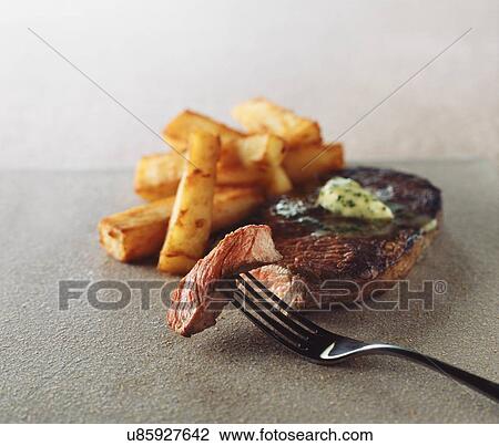Stock Image - Rare steak and chips, garlic butter. Fotosearch