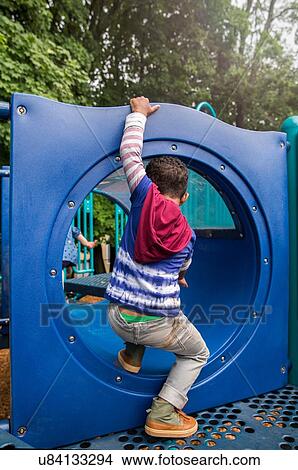 Picture - Rear view of boy climbing playground tunnel. Fotosearch
