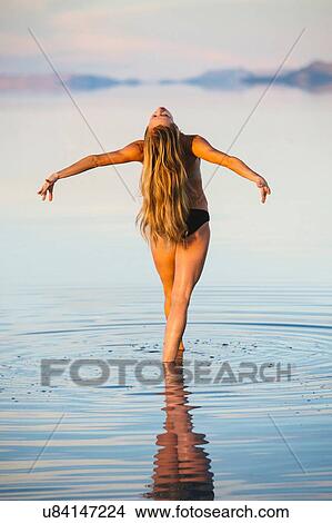 Picture - "Rear view of female dancer poised showing long blond hair in lake, Bonneville Salt Flats, Utah, USA". Fotosearch
