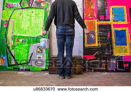 Rear view of male artist standing in front of painted canvases View Large Photo Image Stock Image - Rear view of male artist standing in front of painted canvases. Fotosearch