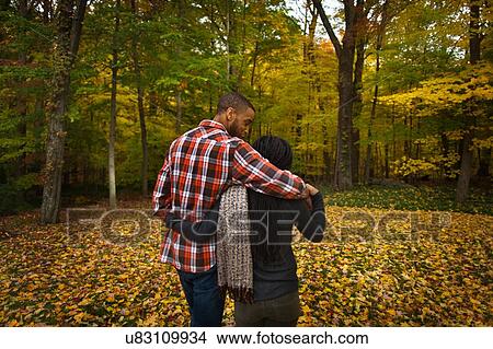 Rear view of mid adult couple strolling in autumn forest View Large Photo Image Picture - Rear view of mid adult couple strolling in autumn forest. Fotosearch