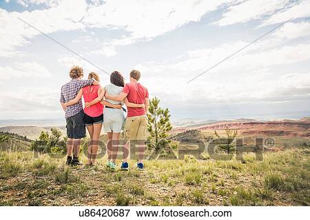 Stock Photo - Rear view of teenage girl and adult friends looking out over landscape, Bridger, Montana, USA. Fotosearch