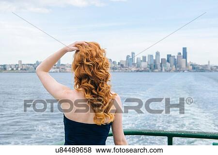 Stock Photo - "Rear view of woman looking at skyline from passenger ferry on Puget Sound, Seattle, USA". Fotosearch