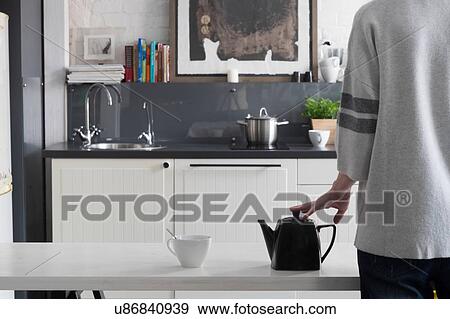 Rear view of woman waiting for tea to brew on kitchen table View Large Photo Image Stock Photo - Rear view of woman waiting for tea to brew on kitchen table. Fotosearch