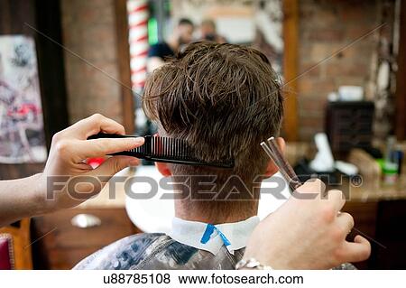 Stock Photo - Rear view of young man in barbershop having haircut. Fotosearch