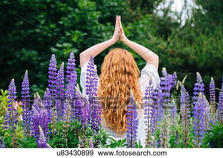 Rear view of young woman meditating with hands together amongst purple wildflowers View Large Photo Image Stock Photo - Rear view of young woman meditating with hands together amongst purple wildflowers. Fotosearch
