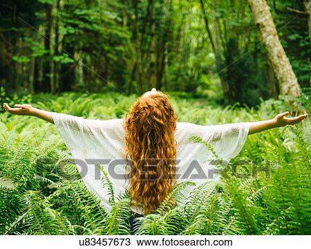 Rear view of young woman with long red hair with arms open amongst forest ferns View Large Photo Image Stock Image - Rear view of young woman with long red hair with arms open amongst forest ferns. Fotosearch